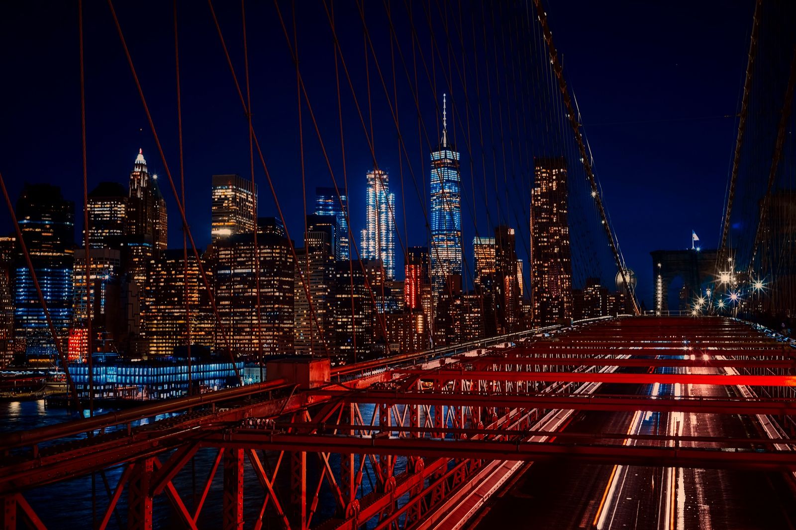 The Manhattan skyline lit at night, seen from the Brooklyn Bridge